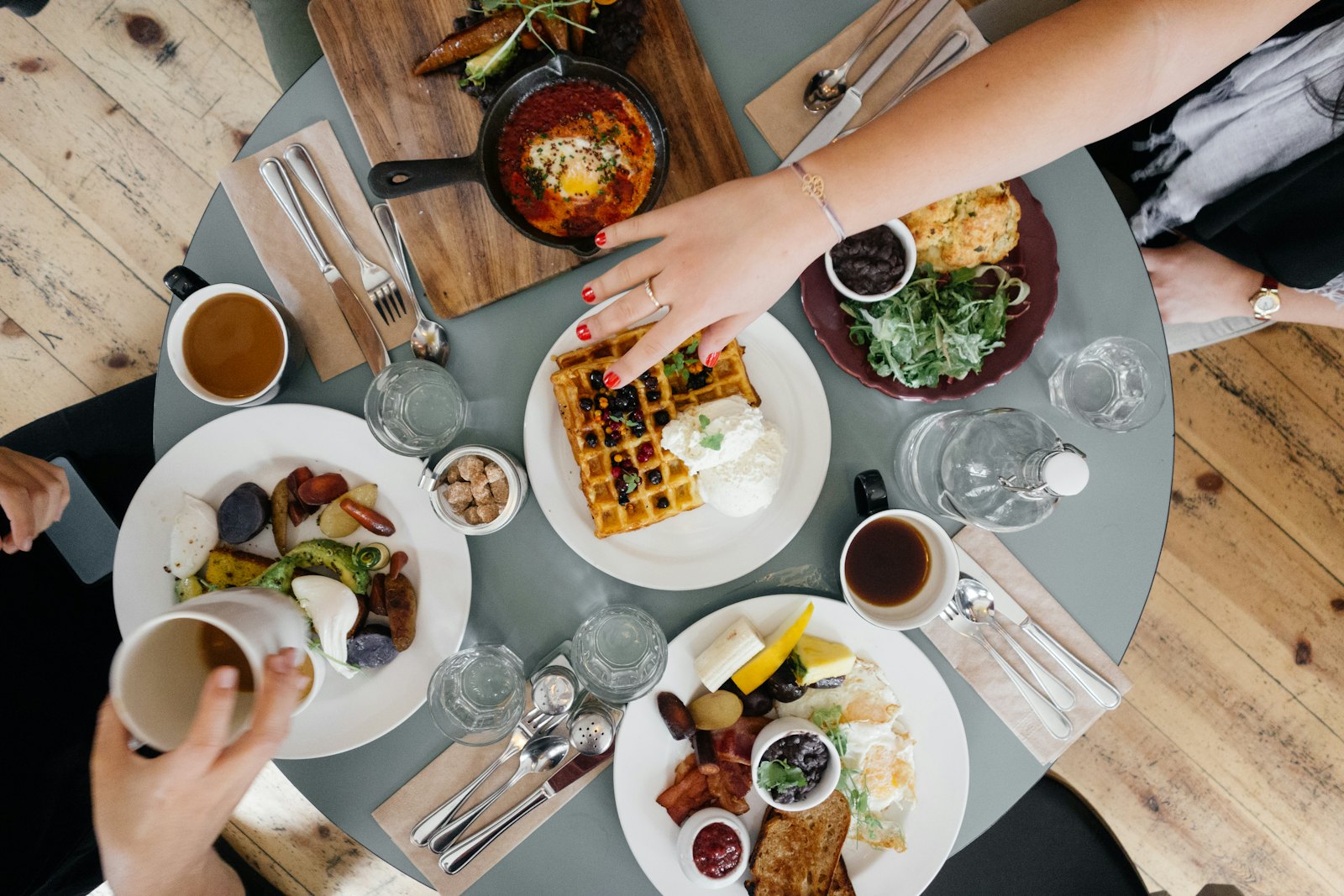 Mesa vista de cima com vários pratos, café e waffles